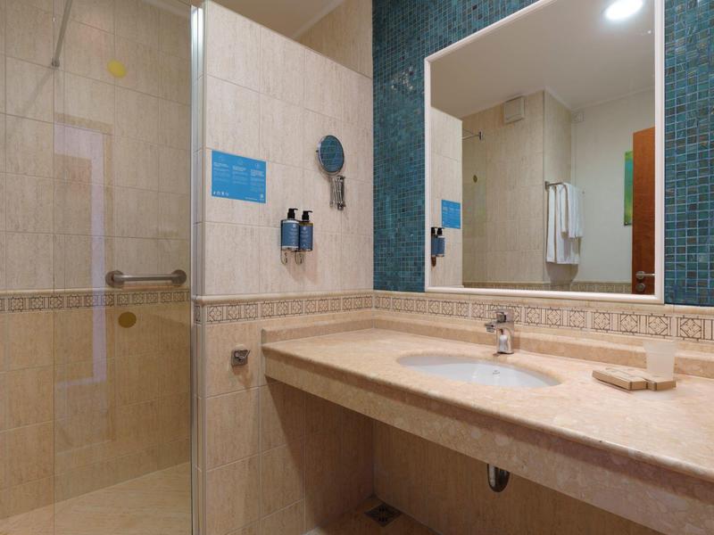 Lichte badkamer met grote spiegel, wastafel en glazen douchecabine