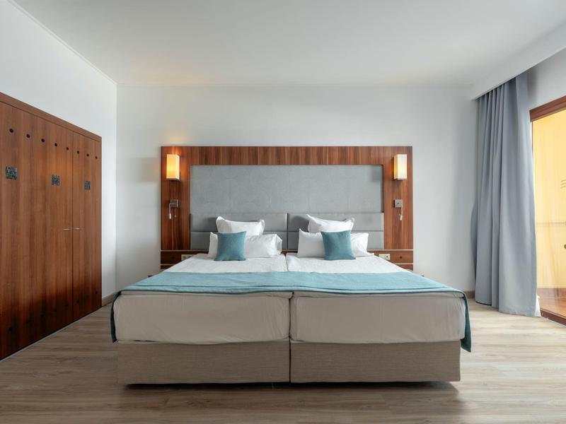 Moderne slaapkamer met tweepersoonsbed, houten accenten en toegang tot balkon met uitzicht buiten.