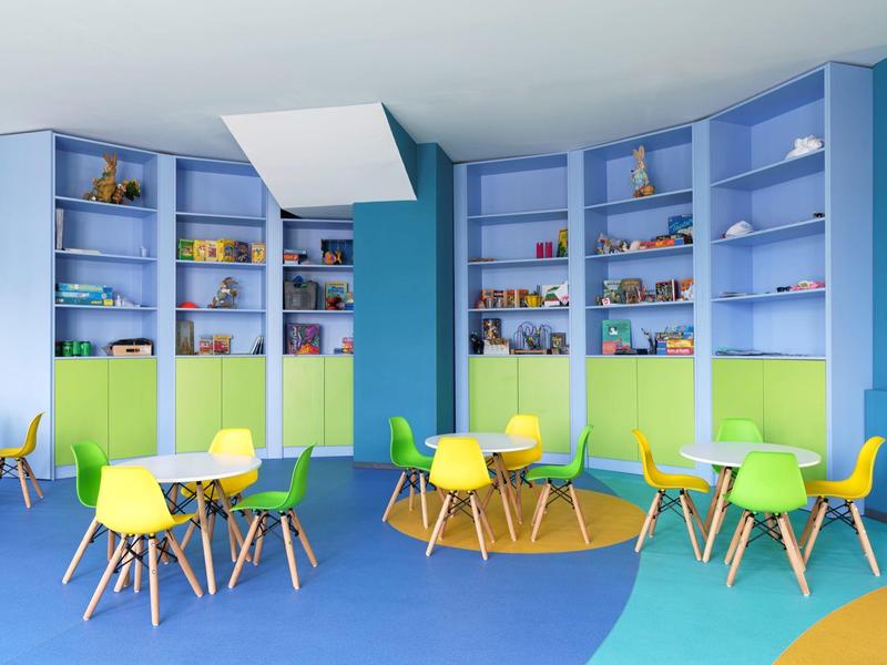 Kleurrijke wachtruimte met gekleurde stoelen en rekken, helder en uitnodigend ingericht.