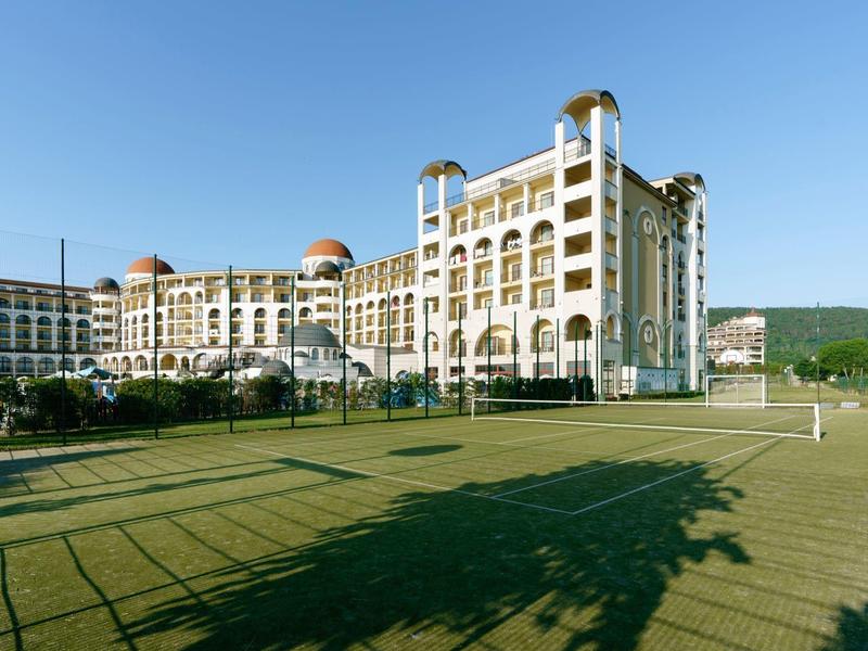 Groot hotelgebouw met een gravelbaan ervoor en een blauwe lucht
