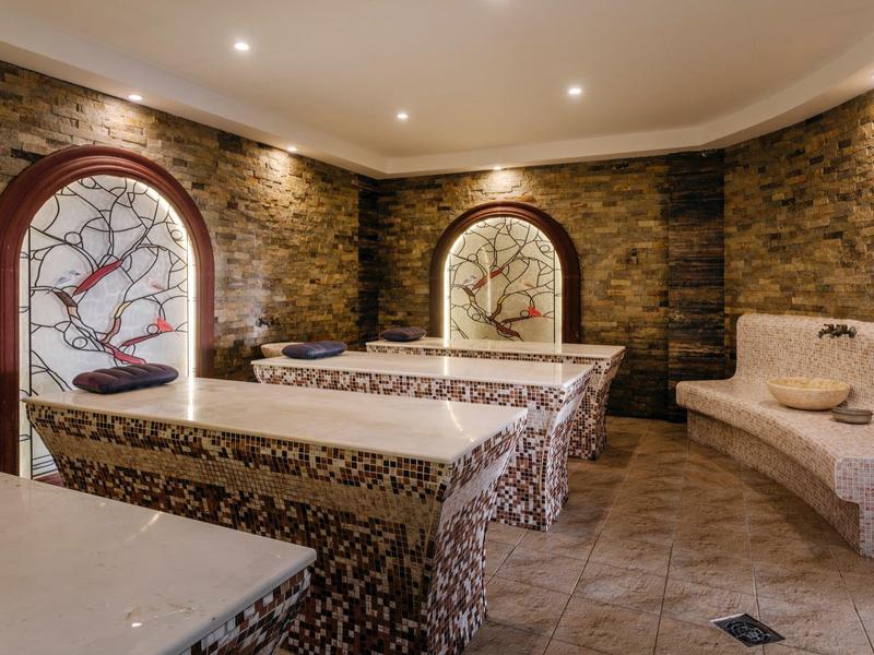 Gezellige wellnessruimte met massagetafels en decoratieve stenen en houten wandelementen.