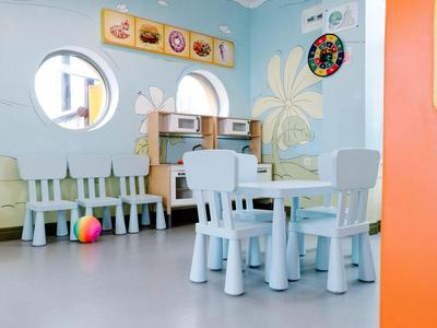 Lichte kinderspeelruimte met wit meubilair en kleurrijke bal op blauwe achtergrond.