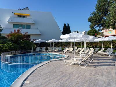 Moderner Hotelpoolbereich mit Liegestühlen und Sonnenschirmen neben rundem Pool.