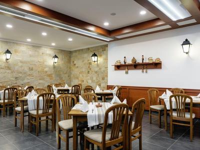 Elegantes Restaurant mit Holztischen und Stühlen, weißen Tischdecken und Steinwand.