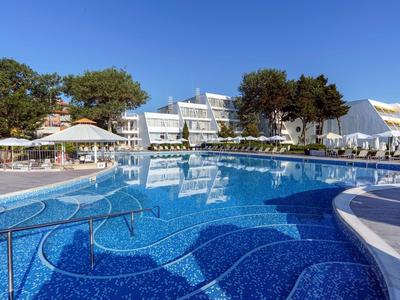 Moderner Hotelpool mit Sonnenschirmen und Liegestühlen bei klarem Himmel.