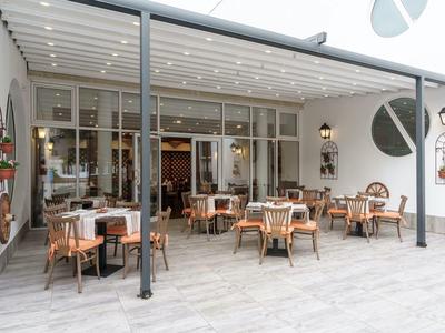 Moderne buitenruimte van een hotel met tafels en stoelen onder een zonnescherm.