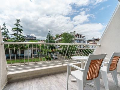 Balkon met witte stoelen met uitzicht op een groen gazon en huizen onder een bewolkte lucht.