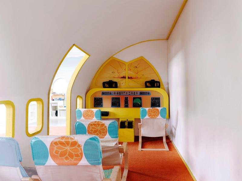 Interieur met kleurrijke stoelen en gele planken in een moderne, stijlvolle ruimte.