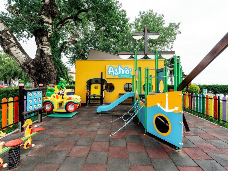 Kleurrijke kinderspeelplaats met klimrek, glijbaan en speelgoedauto's, omgeven door een hek