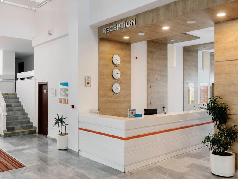 Moderne hotelreceptie met helder balie en klokken aan de muur.