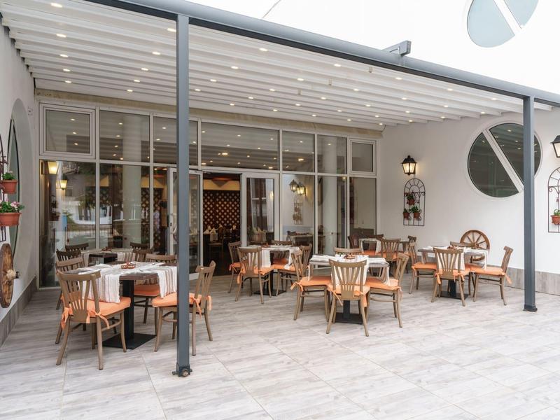 Moderne buitenruimte van een café met tafels en stoelen onder een overdekte ruimte.