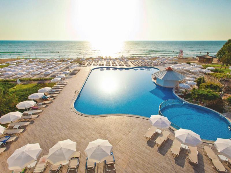 Zwembad met ligstoelen op het strand bij zonsondergang.