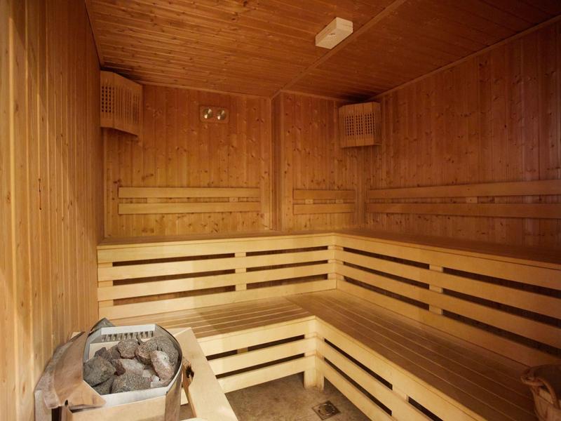 Wooden sauna with benches and a sauna heater in the corner.