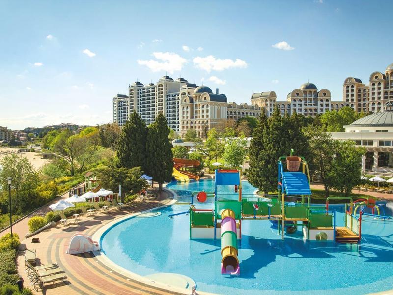 Hotel pool with water playground and surrounding gardens near the coast.
