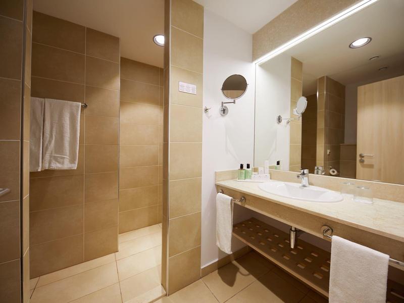 Modern bathroom with large mirror, double sinks, and glass shower.