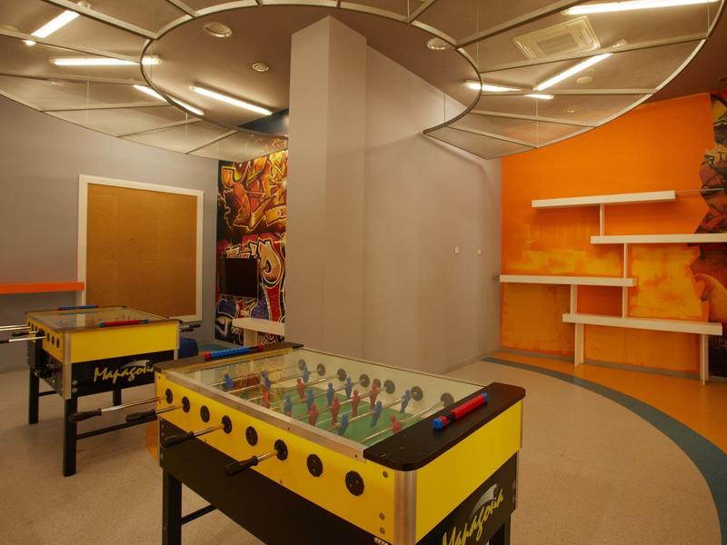 Game room with foosball and table tennis in a warmly lit space.