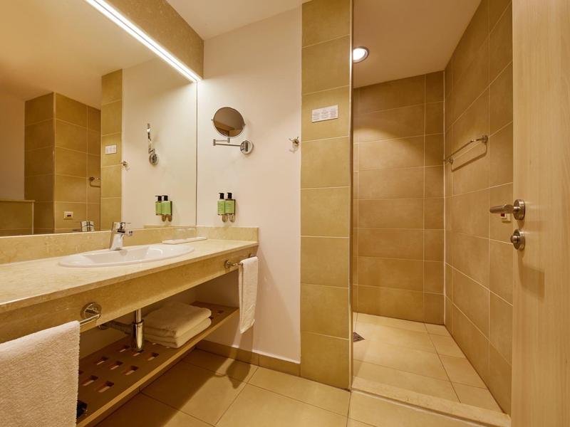 Modern bathroom with large shower and wide sink in neutral tones.