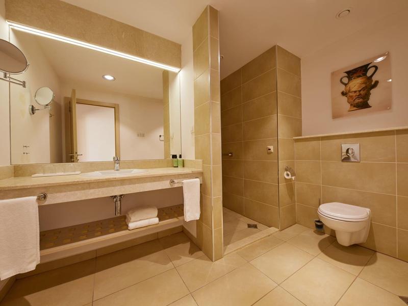 Modern bathroom with large mirror wall, double sinks, and wall-mounted toilet.