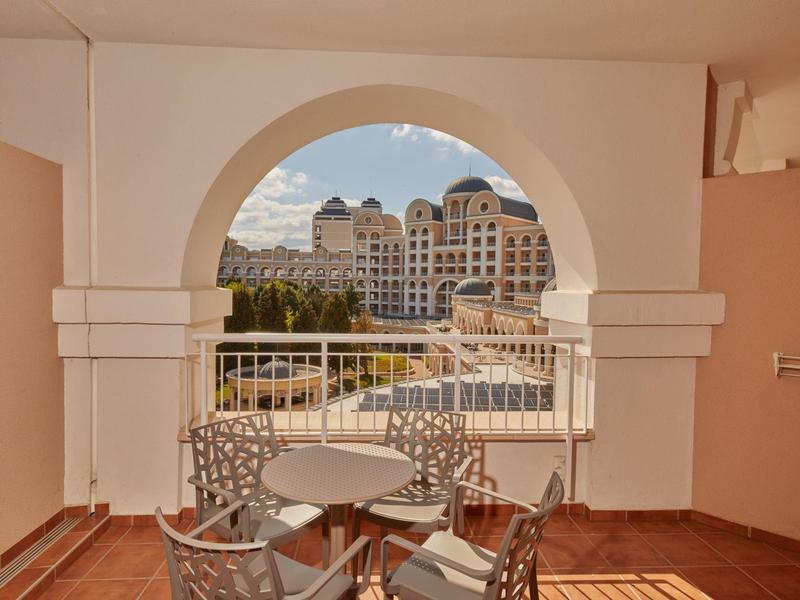 View through an archway to an outdoor area with pool and elegant buildings in the background.