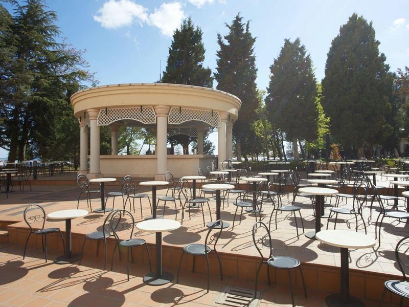 An illuminated outdoor pool in front of a hotel building at sunset.