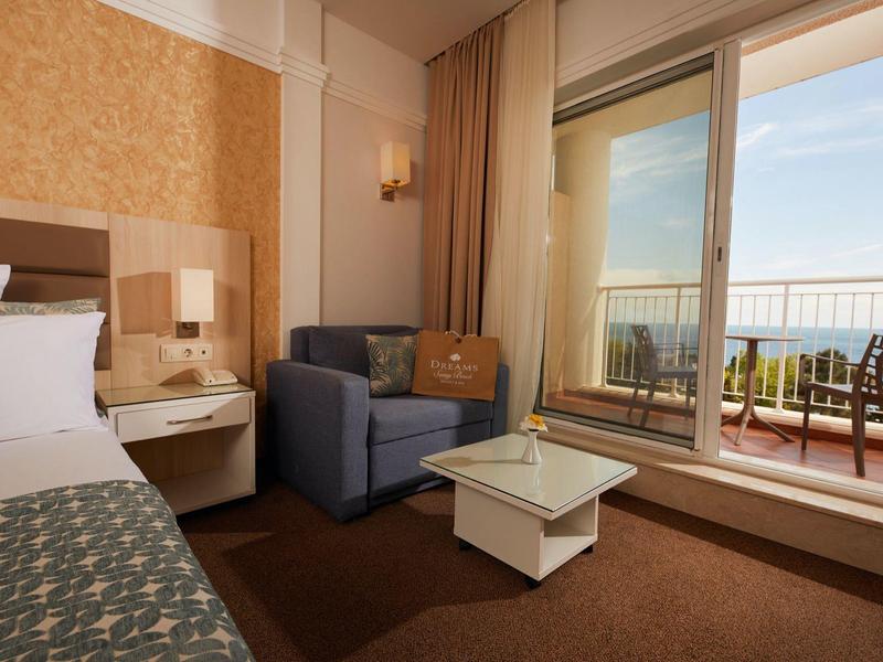 Cozy hotel room with balcony, sofa, table, and sea view.