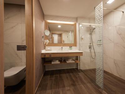 Modernes Badezimmer mit Holzdekor, Glas-Dusche, großem Spiegel und wandmontiertem WC.