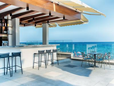 Moderna zona de bar al aire libre con taburetes y mesas con vistas al mar.