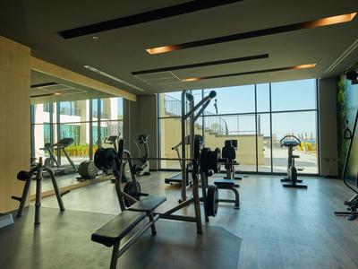 Equipamiento moderno de gimnasio en una sala luminosa y espaciosa con grandes ventanas y vistas.