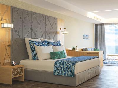 Küstenlinie mit Sandstrand, grünem Ufer und weißen Hochhäusern vor klarem blauem Himmel.