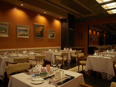 Gemütlicher Restaurantraum mit gedeckten Tischen, Holzstühlen und warmen braunen Wänden.