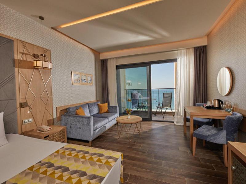 Modernes Hotelzimmer mit Doppelbett, Sofa, Schreibtisch, Balkon und Meerblick.