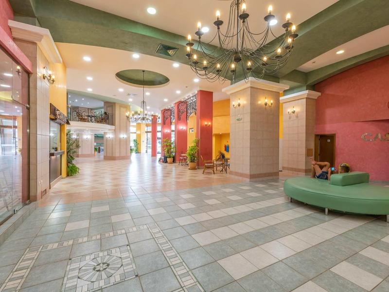 Spacious, brightly lit indoor area with seating, colorful columns, and chandeliers.