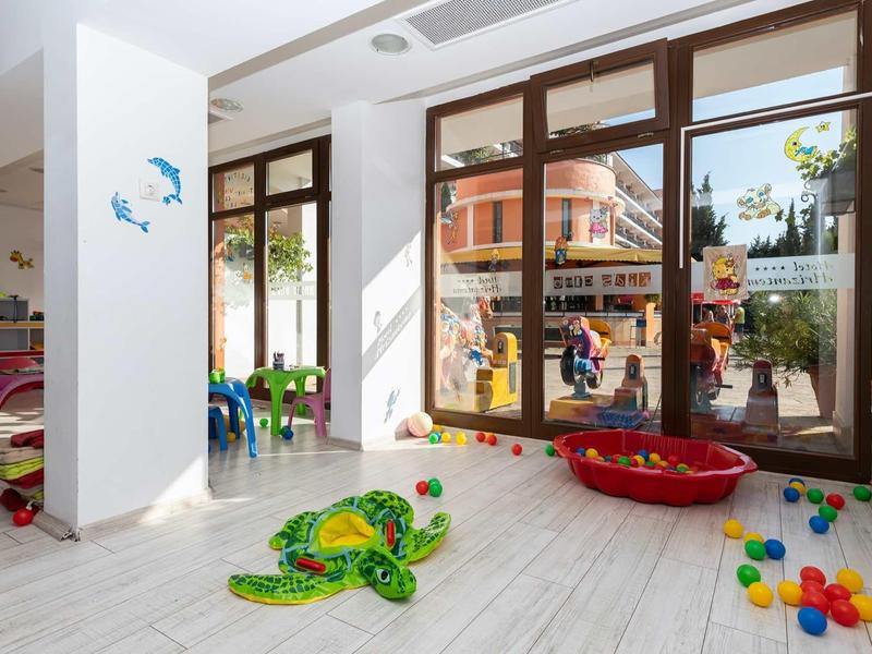 Bright children's playroom with large windows, colorful toys, and seating areas.