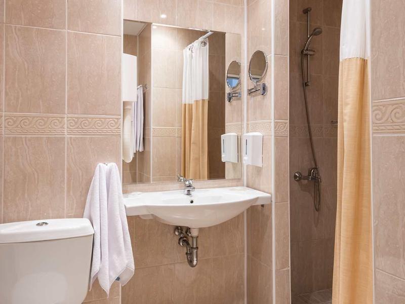 Modern bathroom with sink, toilet, and shower with curtain in warm beige tones.