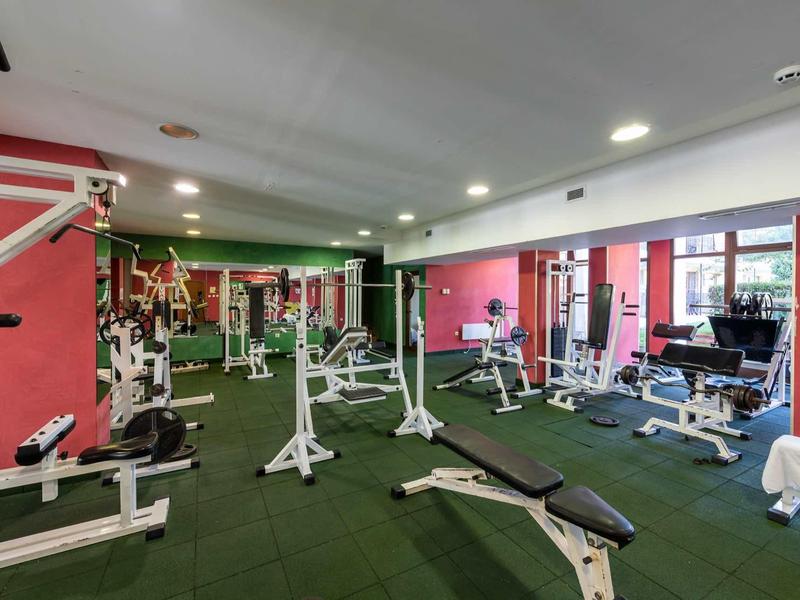 Gym room with various workout equipment and green rubber flooring.