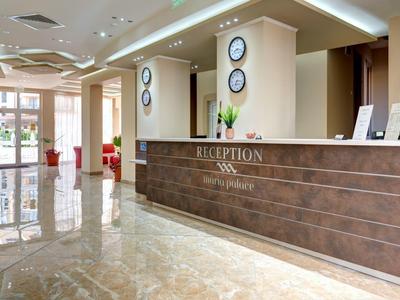 Modern hotel lobby with reception desk, marble floor, and bright walls.