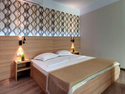 Cozy double bed with brown bedspread and nightstands in a modern hotel room.
