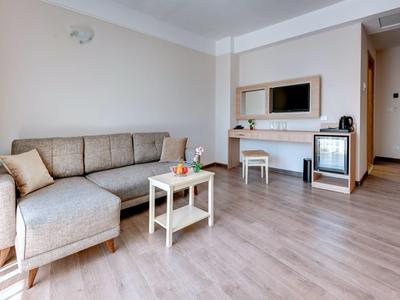 Living area with beige sofa, small table, and TV in modern hotel room.