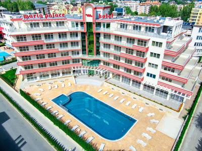 Large hotel with red and white facade and large swimming pool in the courtyard.