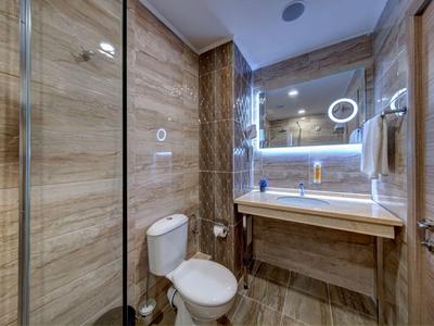 Modern bathroom with illuminated mirror, toilet, and shower cabin featuring wood-look tiles.