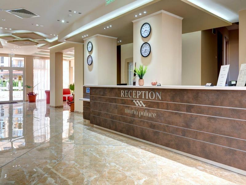 Modern hotel lobby with reception desk, marble floor, and bright walls.