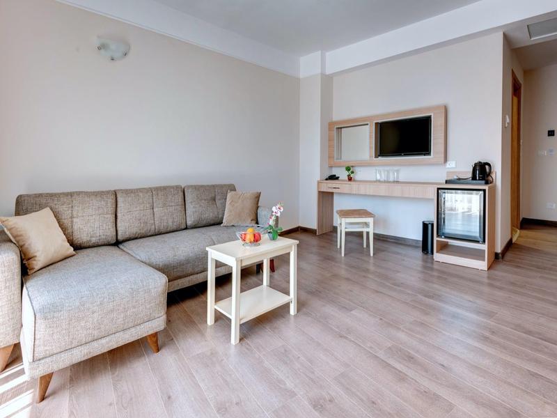 Living area with beige sofa, small table, and TV in modern hotel room.