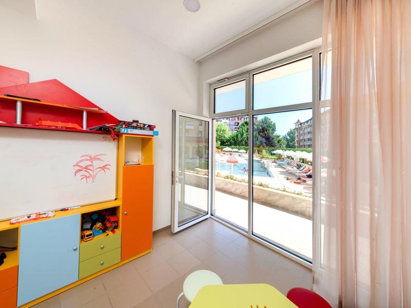 Bright children's playroom with colorful furniture and large glass sliding door to garden.