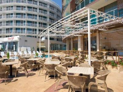 Outdoor area of a hotel with a round building, tables, and chairs under a pergola.