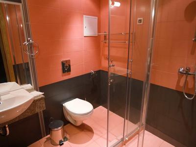 Compact bathroom with toilet, sink, and shower, designed in orange and black.