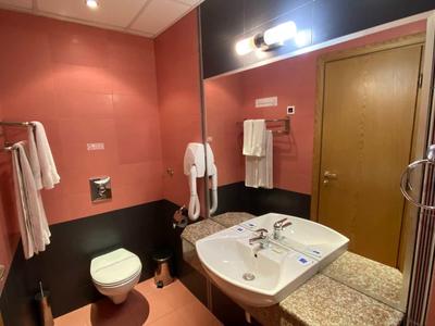 Small bathroom with sink, toilet, and red walls in a hotel room.