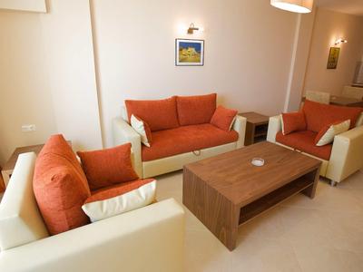 Bright living room with two white sofas with orange cushions and a wooden table.