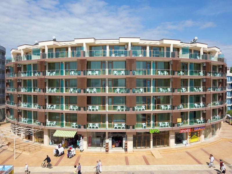 Round hotel building with multiple balconies and shops on the ground floor.