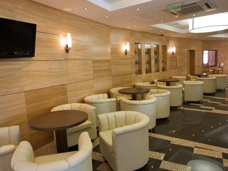 Modern hotel lounge with round tables, comfortable white chairs, and wooden paneling.