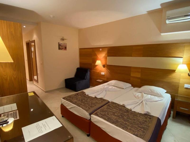 Modern hotel room with two beds, warm lighting, and wooden paneling.
